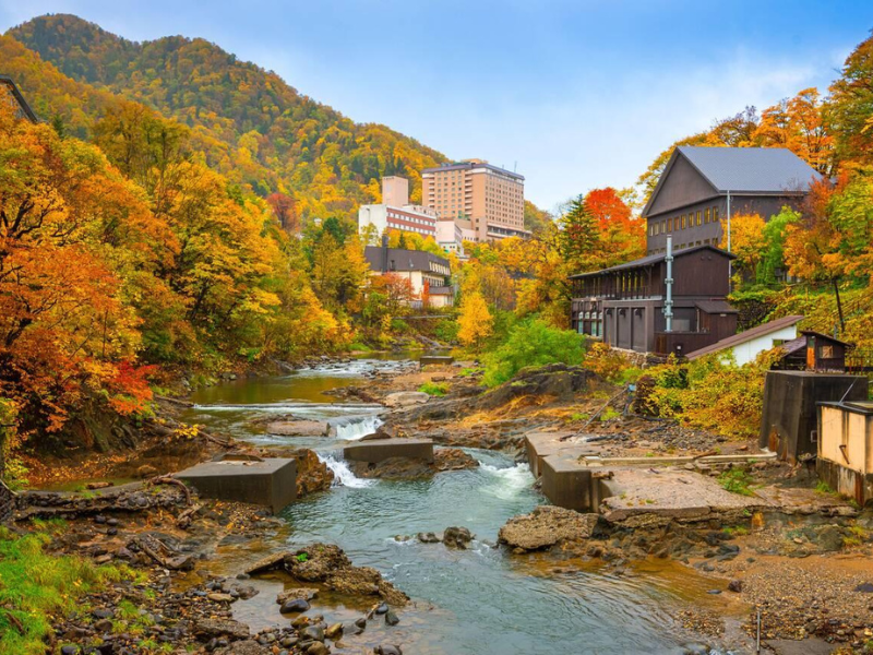 A serene river flowing through a mountain resort in autumn