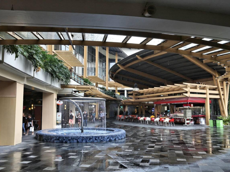 Covered mall area with decorative fountain and restaurant seating