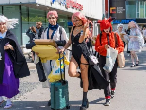 Cosplayers dressed as anime characters walking outside a convention center, carrying merchandise bags