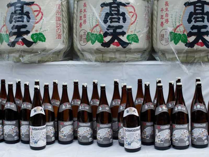 Large sake barrels and neatly arranged bottles on a table