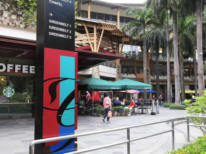 Outdoor café seating at Greenbelt Mall under lush palm trees