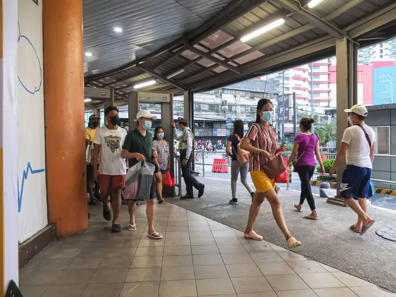 Masked commuters walking through train station entrance under roof