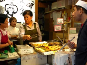 Locals ordering street food at a busy Osaka food stall