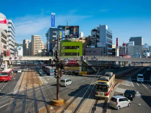Busy street in Nagasaki with trams, cars, and buildings