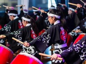 Japanese performers playing Taiko drums in traditional black outfits