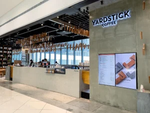 Yardstick Coffee exterior with signage and illuminated wooden ceiling details