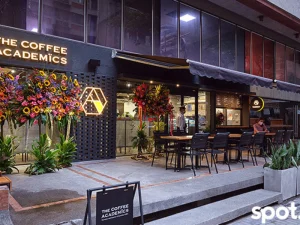 The Coffee Academics storefront decorated with fresh flowers at night