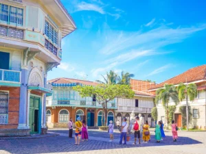Tourists exploring vibrant heritage houses under a bright blue sky