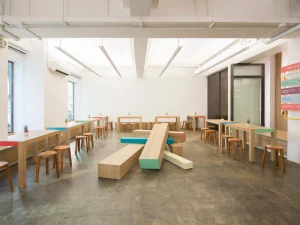 Minimalist coffee shop interior with wooden tables and colorful benches.