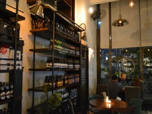 Shelf filled with wine bottles inside Refinery café at night.