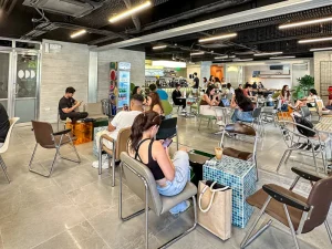 A spacious, modern cafe interior filled with people sitting at tables and enjoying their food and drinks, creating a lively atmosphere.