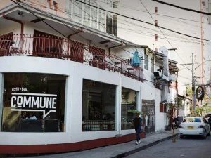 The outside view of Commune cafe with its iconic signage, red railing, and bustling urban surroundings.