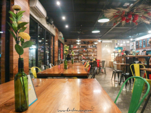 Interior of Kandle Café with wooden tables, metal chairs, and wine bottle vases, creating a cozy and rustic ambiance