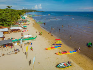 Beach with colorful kayaks, people enjoying the sunny shoreline. 