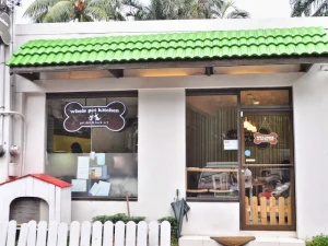 A pet café with a green roof, white walls, and a glass door featuring a sign that reads "Whole Pet Kitchen