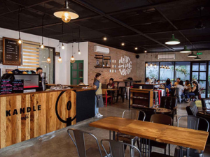 Counter area of Kandle Café with wooden accents, industrial lighting, and a welcoming atmosphere with patrons enjoying their meals