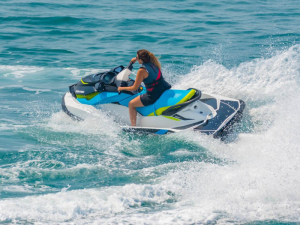 Woman riding a jet ski, making waves in blue water. 