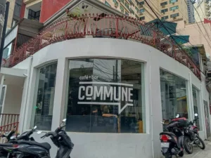 Another exterior shot of Commune Café with its white curved walls, large windows, and a few parked motorcycles in front