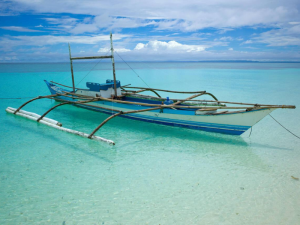 Traditional wooden boat floating on clear turquoise water, bright sky. 