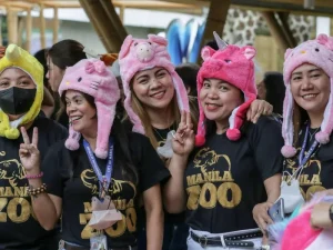 Visitors at the zoo wear colorful animal-themed hats and pose for a photo