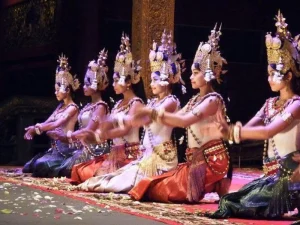 A cultural dance with performers seated on the stage in ceremonial attire