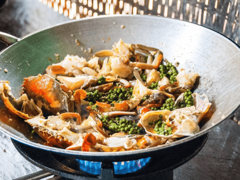 Close-up of seafood and vegetables cooking in a wok on a stove
