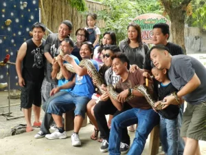 A group of people poses with a large python during a zoo visit