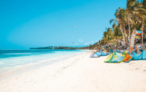 A tropical beach with crystal-clear turquoise waters, lush green cliffs, and white sand, creating a serene and picturesque paradise.