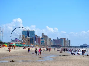 Bustling beach with people enjoying sand, ocean, and skyline views