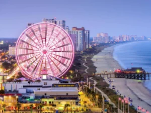 Illuminated Ferris wheel overlooking a beautiful city and beachscape