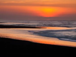 Vibrant sunset reflects on beach waves and glowing shoreline colors