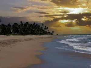 Sunset light breaks through clouds over tropical beach shoreline
