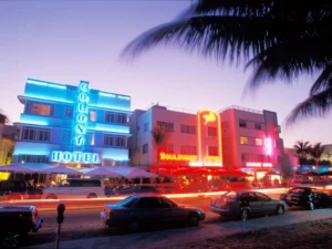 Neon-lit Art Deco buildings with busy streets and palm trees