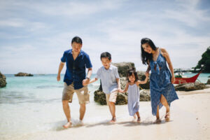 a family of 4 happily walking along the white sand beach of boracay
