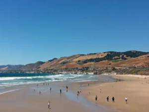 Visitors enjoy wide beach bordered by hills and waves
