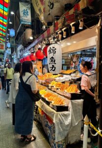 nishiki 5 - Travelpreneur a vendor and customer interacting at an alley of nishiki market