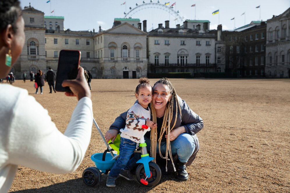 a side view of a woman taking a picture of a mother and a child