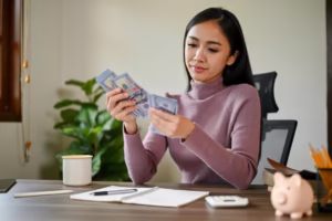 beautiful asian female counting her money table planning her savings