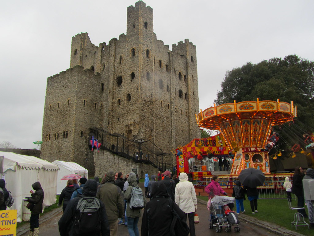 Rochester Castle full of people and festival rides during a seasonal event