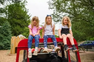 7 Playground - Travelpreneur Eastnor Castle Playground of 3 young children sitting on one of the play furniture
