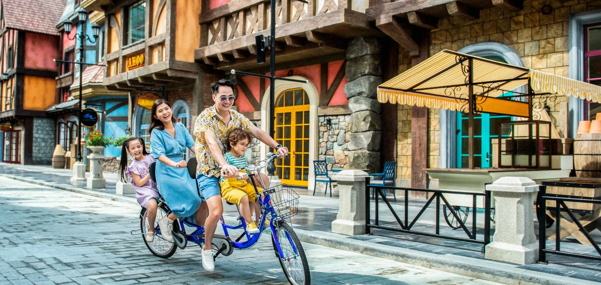 a family of 4 happily riding a bike at VinWonders European Street