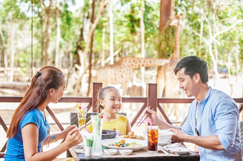 a family of 3 dining at a restaurant at the Vinpearl Safari