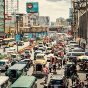 Busy city avenue packed with cars, jeepneys, and pedestrians, illustrating infrastructure pressures from growing tourism