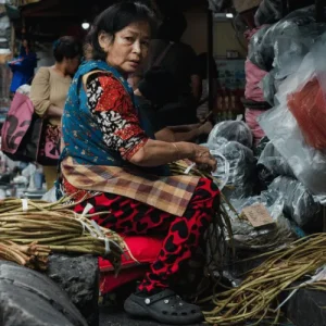 Local vendor selling vegetables at crowded street market, reflecting everyday life behind community-based tourism experiences