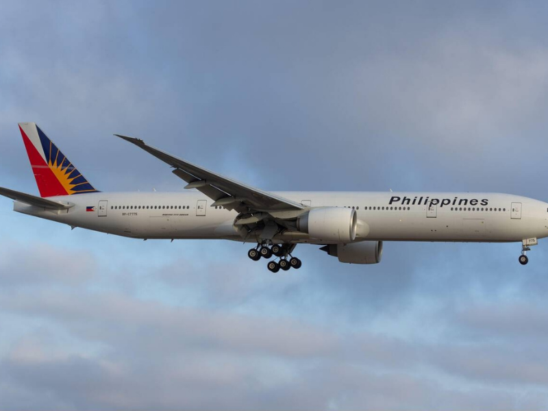 Philippine Airlines jet flies through cloudy sky before landing, representing international air connections supporting tourism