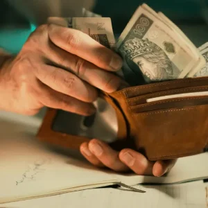 Closeup of traveler counting foreign cash from wallet, highlighting how tourism expenses impact personal budgets