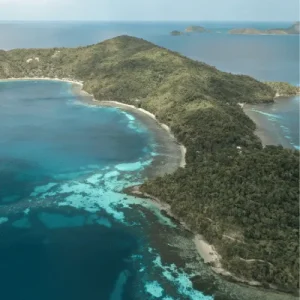 Aerial view of turquoise bay and forested island shoreline, showcasing coastal tourism potential in Philippines