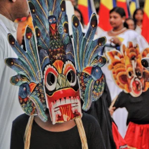 Festival performer wears colorful carved mask in parade crowd, Holidays in the Philippines cultural tradition