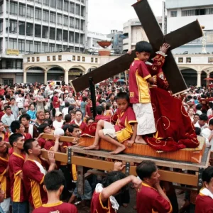 Religious procession carries large cross through crowded street, Holidays in the Philippines faith tradition scene