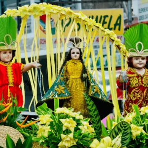Religious Santo Niño statues sit beneath palm-leaf arch and flowers, Holidays in the Philippines devotion
